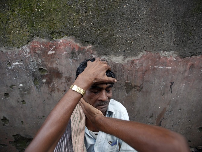 A daily-wage labourer gets a massage by a roadside barber.