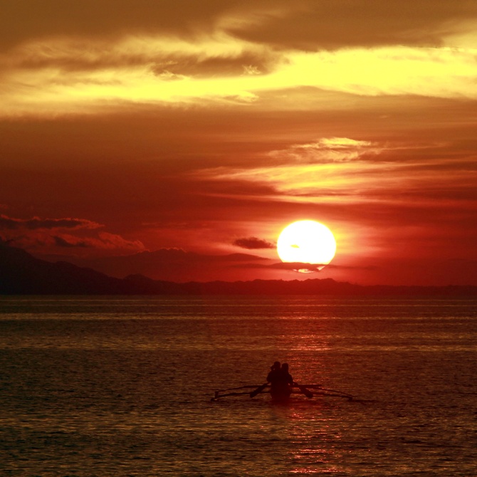 Residents paddle their canoe to go fishing as the sun sets in Mogpog town on Marinduque island, south of Manila, the second largest city of the Philippines.