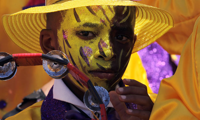 A child waits as brightly coloured revellers sing and dance through the streets of Cape Town during the New Year