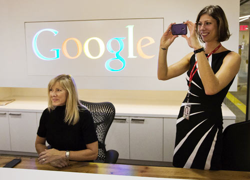 Google employee Andrea Janus takes a picture with her phone as her co-worker Tracy McNeilly looks on at the new Google office in Toronto, November 13, 2012.