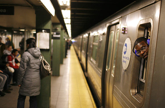 A train conductor leans out his window as a subway car starts down the tracks in New York.
