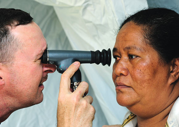 An optometrist uses an ophthalmoscope to check the retina of a patient