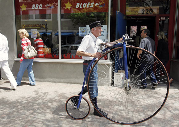 A man walks an old fashioned bicycle down the street at the Watch City Festival celebrating Steampunk in Waltham, Massachusetts May 13, 2012. Steampunk is a movement that explores the notion of what the world might look like had modern technology been available at the turn of the twentieth century.