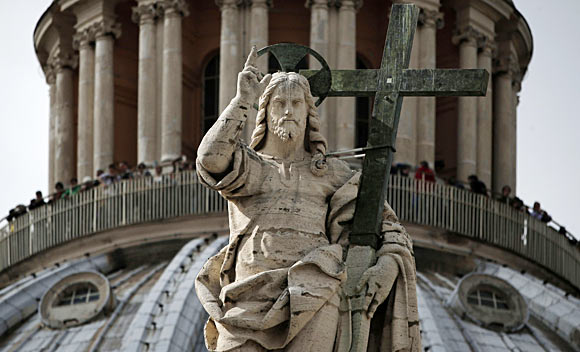 The statue of the Christ is seen in front of the dome of Saint Peter's Basilica at the Vatican.