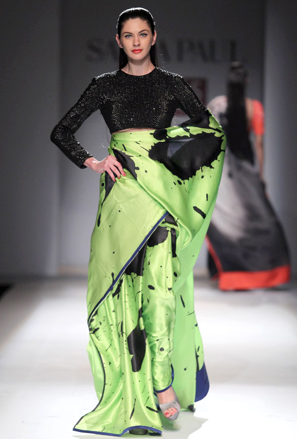 A model sports an ink blot black and green saree with a short black embellished blouse.