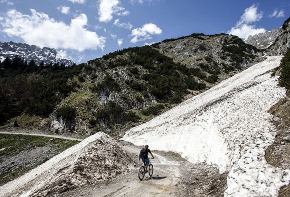A cyclist rides past remnants of a recent winter avalanche, on a sunny spring day in the western Austrian city of Innsbruck.