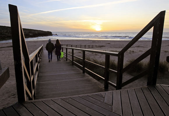 A couple walks to the beach during sunset at Lisandro beach on the Atlantic sea coast of Portugal, 40 km north of Lisbon.