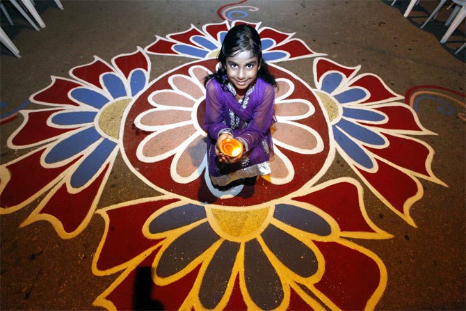 A young lady holds a diya, or oil lamp, in a street during Diwali celebrations.
