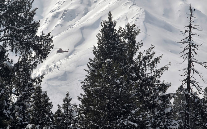 A helicopter carrying heli-skiers flies behind snow-covered trees in Gulmarg, 55 km west of Srinagar.