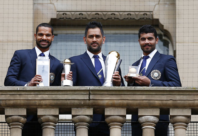 India's cricket players Shikhar Dhawan (L), Mahendra Singh Dhoni (C) and Ravindra Jadeja pose with the ICC Champions Trophy on the balcony of the City Council building in Birmingham, central England, June 24, 2013.