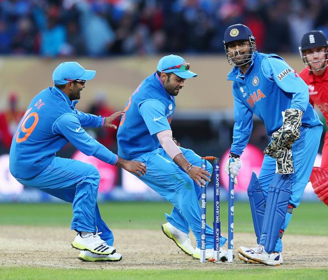 James Tredwell (R) of England cuts a lonely figure as India players Dinesh Karthik (L) Suresh Raina (2L) and MS Dhoni (2R) celebrate their 5 run victory during the ICC Champions Trophy Final match between England and India at Edgbaston on June 23, 2013 in Birmingham, England.