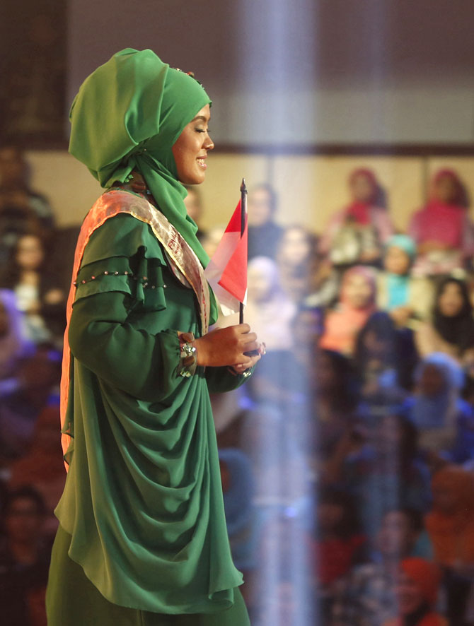 An Indonesian contestant walks onstage with her country's flag.