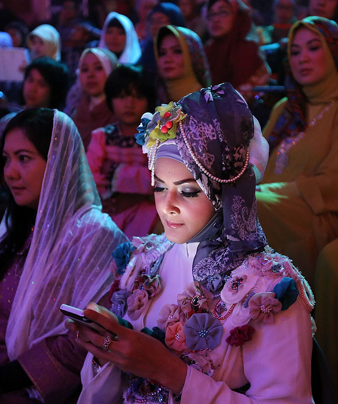 An Indonesian Muslim woman in the audience glances a her phone.