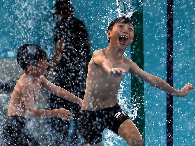Children cool off at a park during a warm day in Singapore