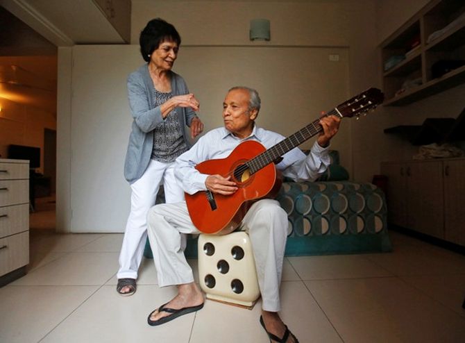 Aruna Gokhale (L), 81, watches as her husband Vidyadhar Gokhale, 84, plays guitar.