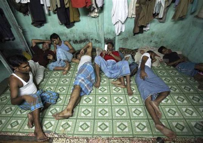 Migrant workers rest inside their one room dwelling in a residential area in Mumbai.