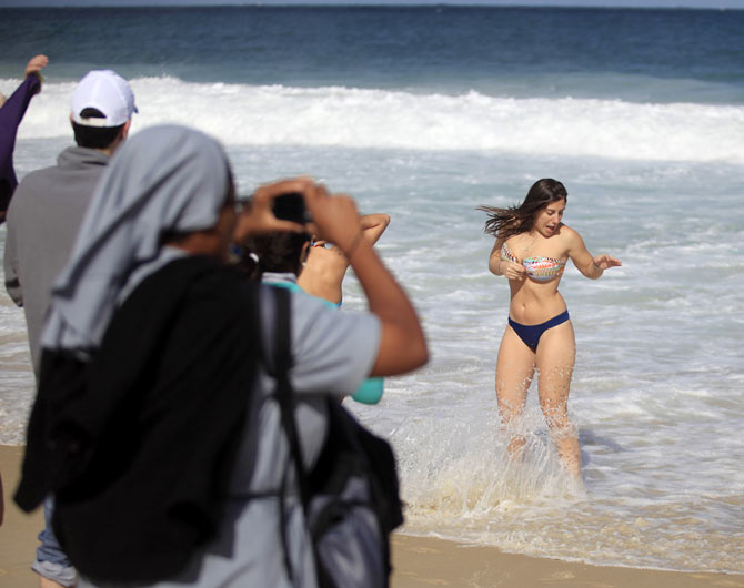 A nun takes pictures of bathers before the arrival of Pope Francis on Copacabana beach in Rio de Janeiro in July last year.