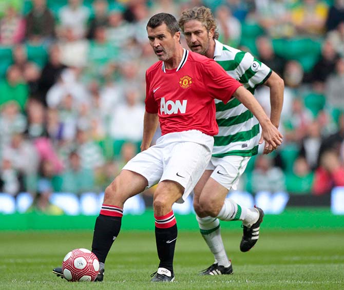 Manchester United Legends Roy Keane passes the ball as Celtic Legends Gerard Butler challenges during their charity soccer match at Celtic Park stadium in Glasgow, Scotland August 9, 2011.