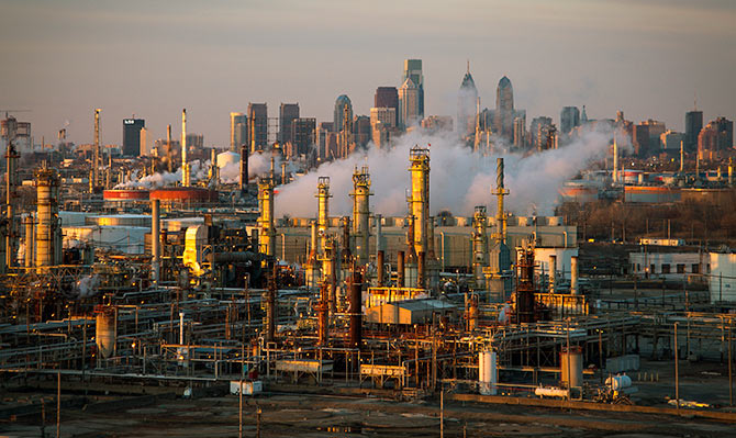 The Philadelphia Energy Solutions oil refinery owned by The Carlyle Group is seen at sunset in front of the Philadelphia skyline.