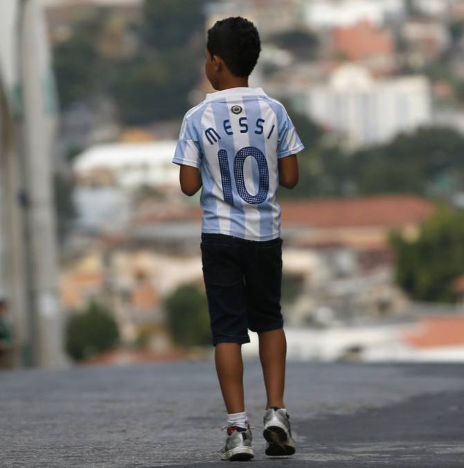 A boy wearing a jersey of Argentine star Lionel Messi walks on a street outside Independencia stadium before the start of the Argentine national team training session in preparation for 2014 World Cup in Belo Horizonte, June 11, 2014.