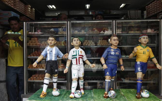 A worker carries sweets next to the models of soccer players that are made of sweets at a bakery shop ahead of the 2014 FIFA World Cup, on the outskirts of Kolkata June 11, 2014. The 2014 World Cup soccer tournament will be held in 12 cities in Brazil from June 12 to July 13.