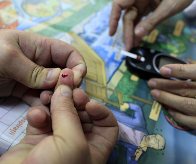 A man squeezes a drop of blood from his finger as diabetes educator Cornelia Cristofor teaches how to perform a blood sugar test at the Nicolae Paulescu National Institute for Diabetes, Nutrition and Metabolic Diseases in Bucharest, November 13, 2012. Diabetes patients are instructed how to carry out blood sugar tests and how to self administrate insulin. November 14 is World Diabetes Day.