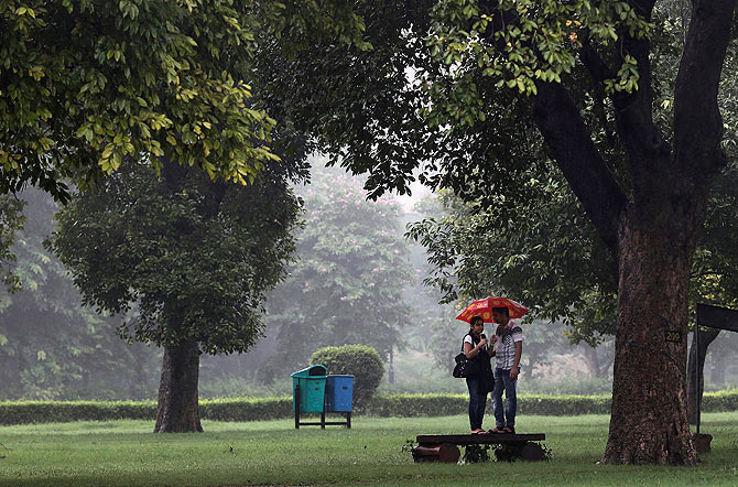 A couple seeks shelter under an umbrella from an unexpected shower.
