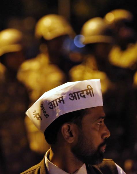 A supporter of Aam Aadmi (Common Man) Party (AAP) stands in front of Indian policemen on guard during a protest outside the headquarters of India's main opposition Bharatiya Janata Party (BJP) in New Delhi March 5, 2014. The writing on the caps reads I am a common man.