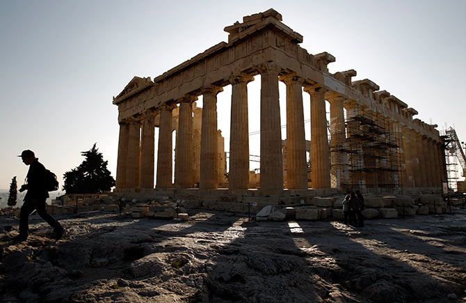 A tourist walks in front of the temple of the Parthenon at the Acropolis in Athens.