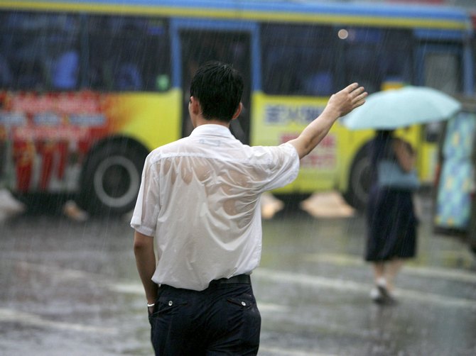Good luck trying to get a cab! A man gestures for a taxi in the rain in Beijing.