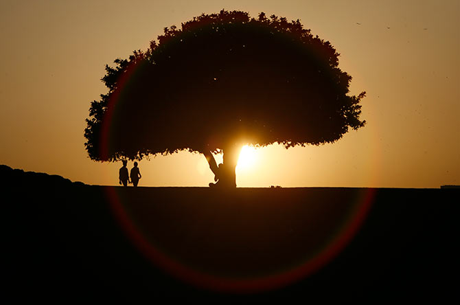 People are silhouetted against the setting sun at a park in New Delhi.