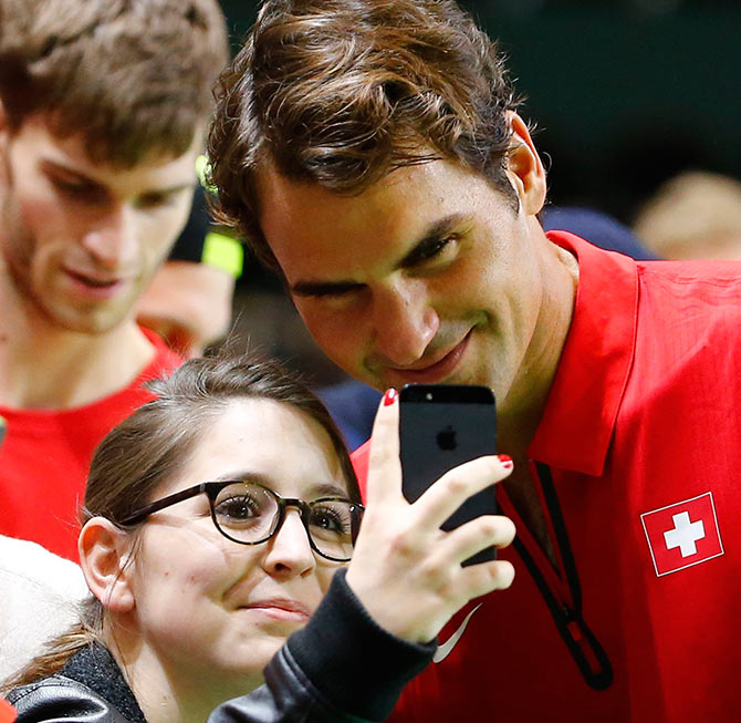 Switzerland's Roger Federer poses with a fan for a selfie after winning his Davis Cup quarter-final tennis match against Andrey Golubev of Kazakhstan in Geneva April 6, 2014.