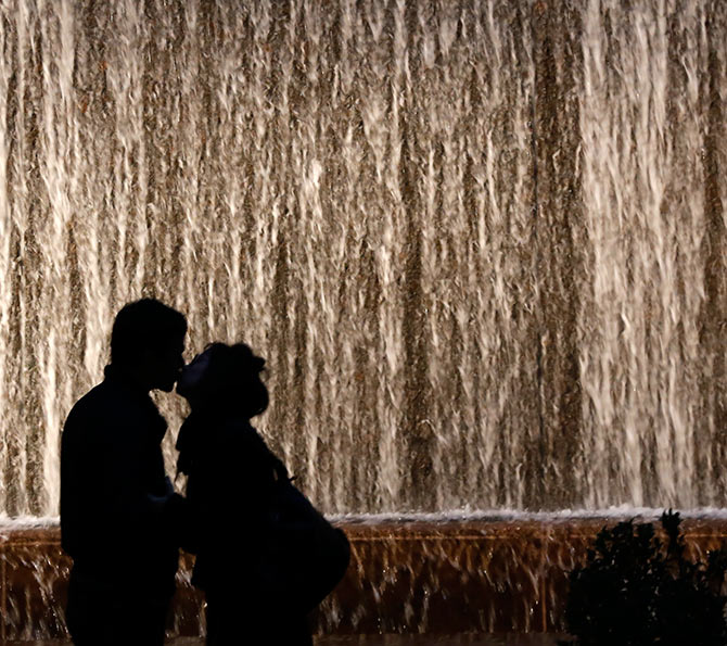 A couple is silhouetted as they kiss in front of a wall waterfall in a small park in New York City November 8, 2013.