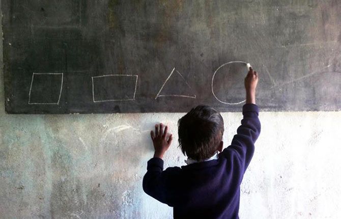 A student from Habib Hassan High School, Brambe, Ranchi writes on a black board