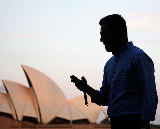 An office worker uses his mobile phone in front of the Sydney Opera House as he leaves Sydney's Central Business District