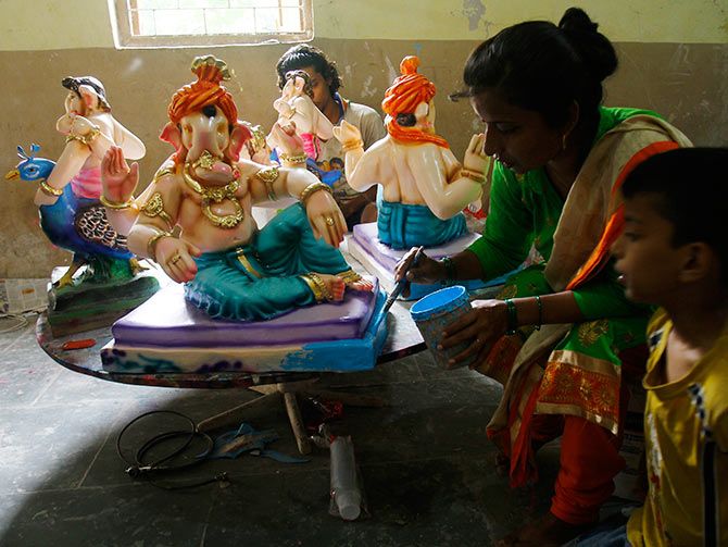 A woman artisan painting an idol at the workshop.