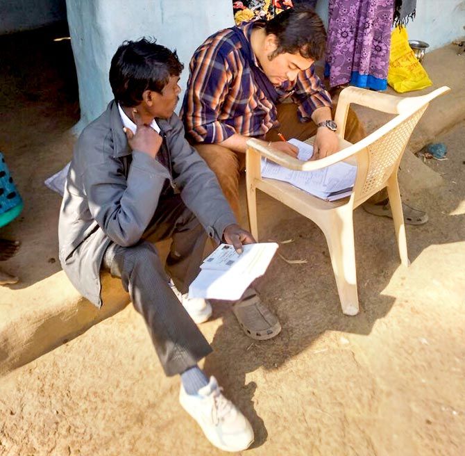 Mangesh helps a villager fill out a form