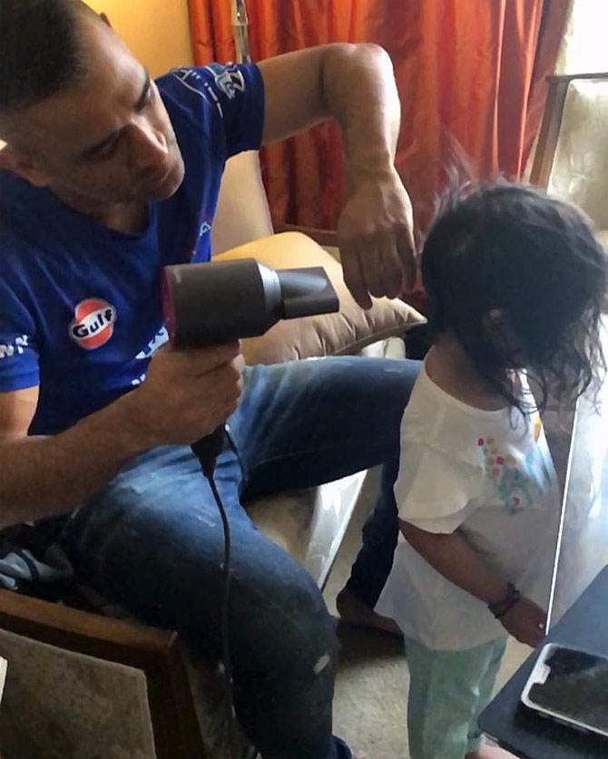 Mahendra Singh Dhoni dries his daughter's hair.