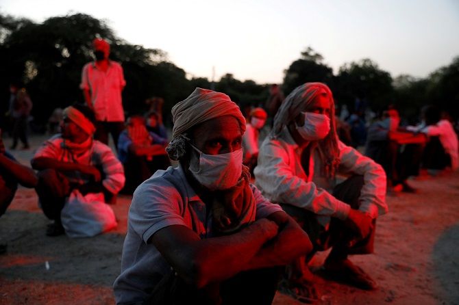 Daily wage workers and homeless people wearing protective masks wait on the banks of Yamuna river as police officers arrange buses to transfer them to a shelter, after India extended a nationwide lockdown. Photograph: Anushree Fadnavis/Reuters. 