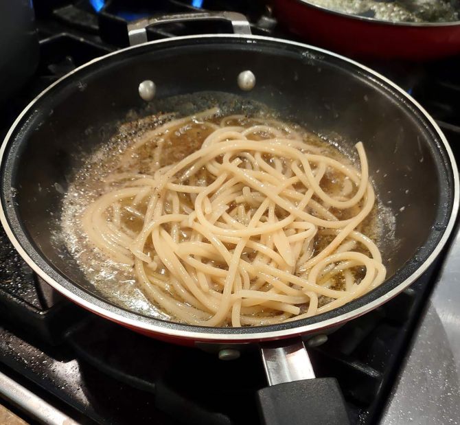 Adding the al dente pasta and water to pepper and butter