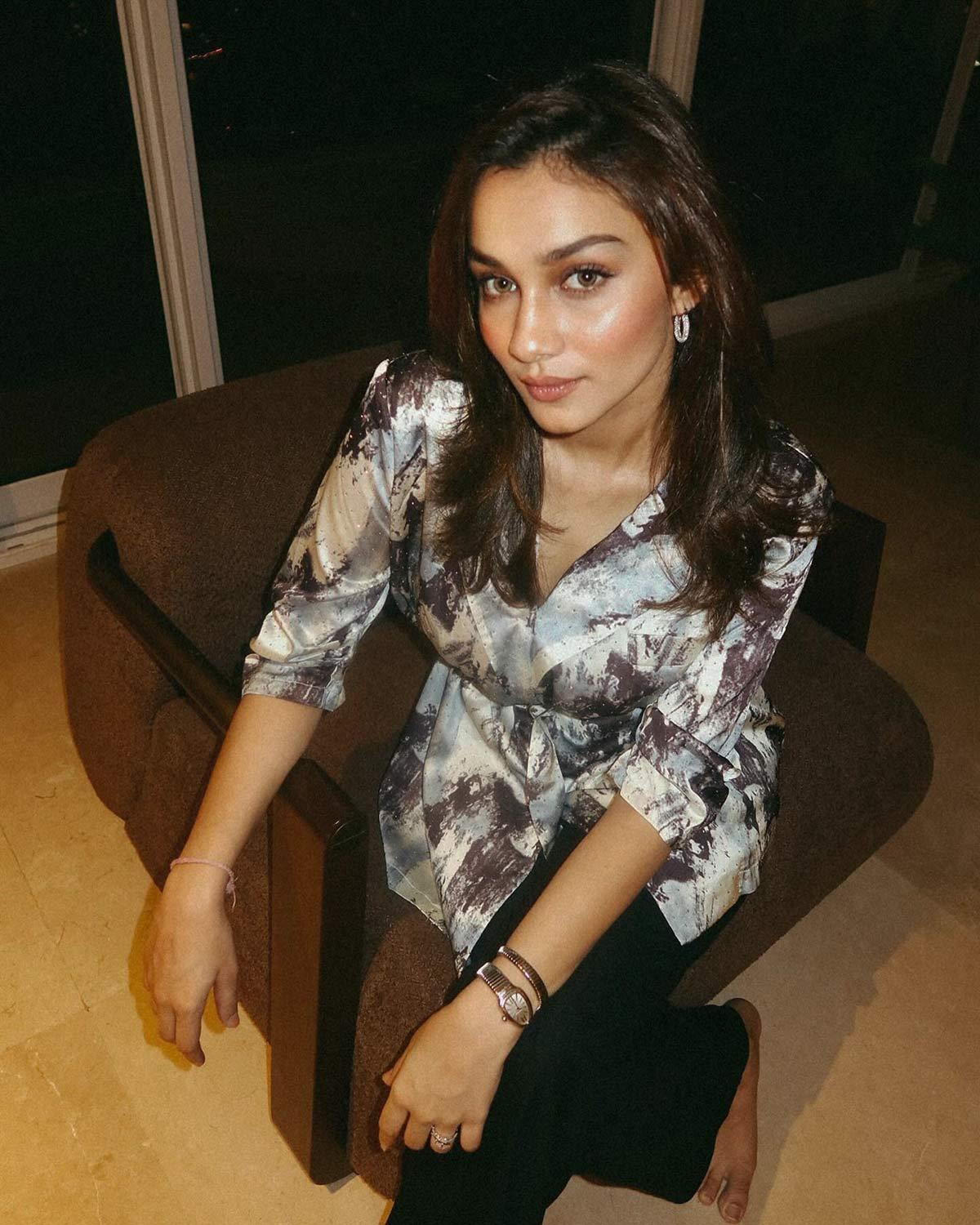  Alfia is wearing bold printed tie-up shirt, sleek black jeans, and a sophisticated Bvlgari Serpenti watch.