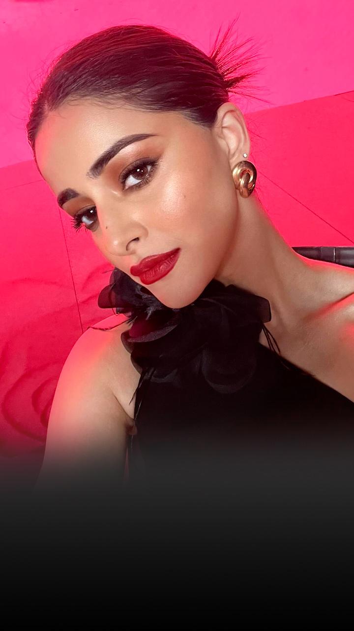 Ananya Panday is wearing a black dress; her hair is in a top knot.