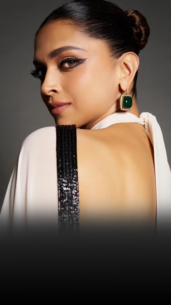 Deepika Padukone is wearing a white sari; her hair is in a top knot.