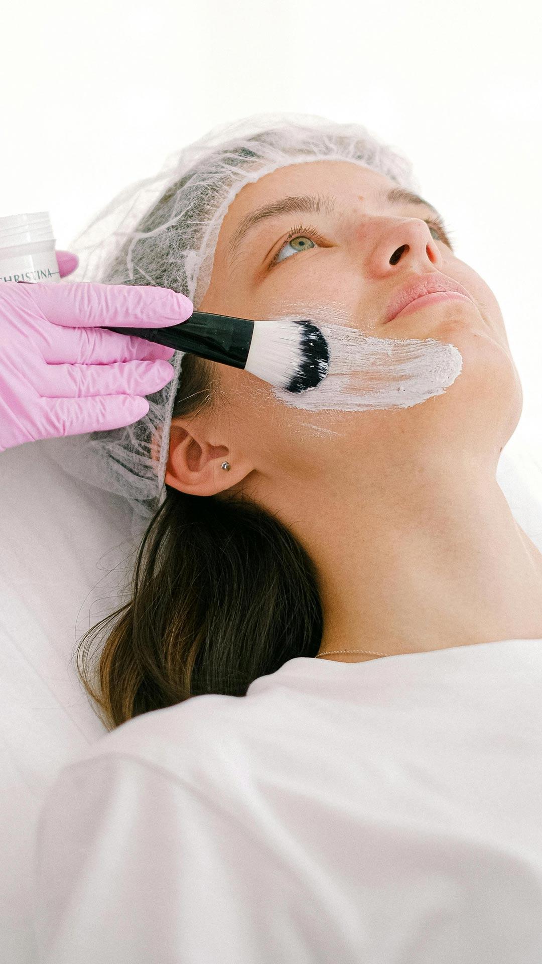 Cosmetologist Applying Ointment on a Woman Face with a Brush