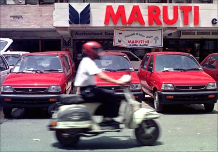 A motorcycle drives past new Maruti cars outside a New Delhi showroom.