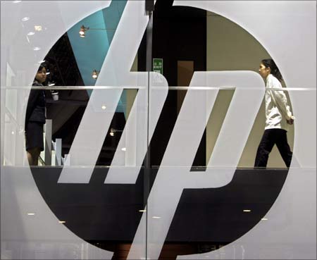 An employee walks past a Hewlett-Packard logo.