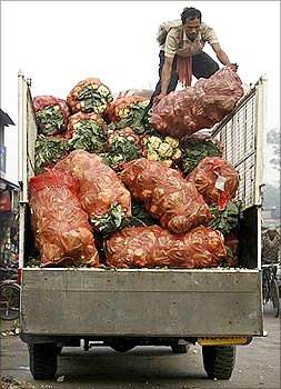 A labourer arranges sacks of vegetables on a truck.