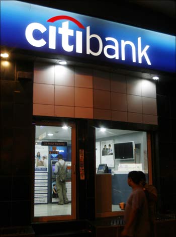 People walk past an ATM counter of Citibank in Mumbai.