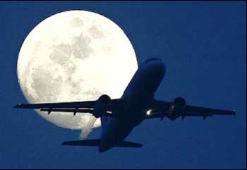 A passenger aircraft is silhouetted against the rising moon in New Delhi.