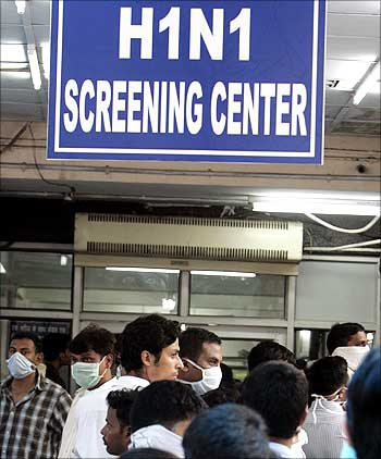 People wearing masks wait in a queue for a H1N1 flu screening at a hospital in New Delhi.